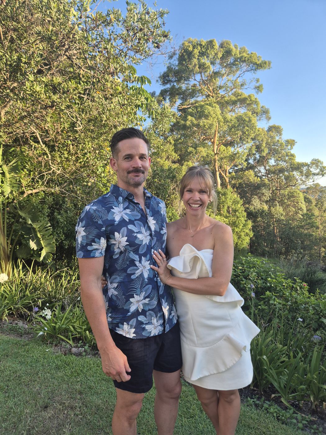 Sally and her husband smiling together outdoors in the late-afternoon sun
