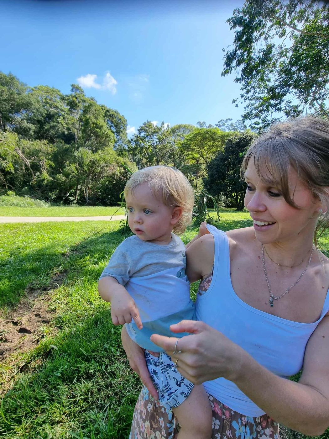 Sally smiling with her youngest son in a sunny green park
