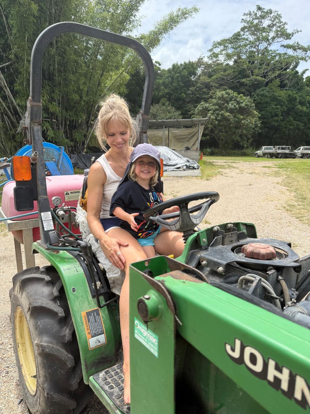 Sally sitting on a green tractor with her son on her lap